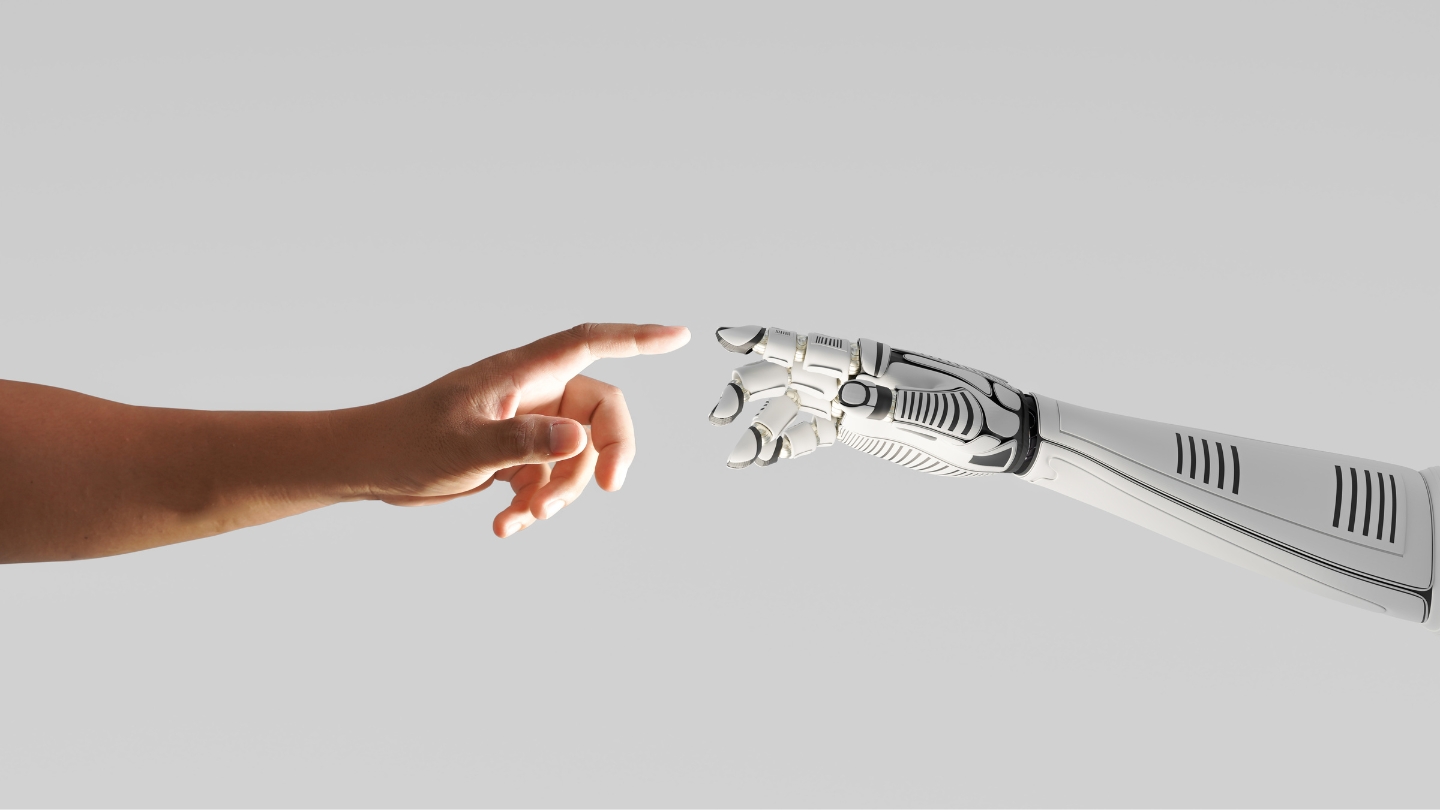 A human arm and robot arm reaching to touch fingertips; representing the union of humans and AI.