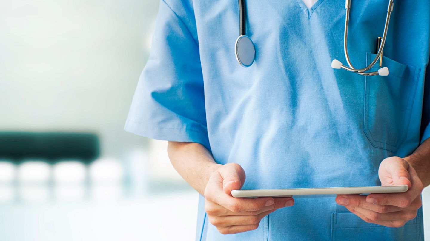 A person wearing scrubs holding a tablet