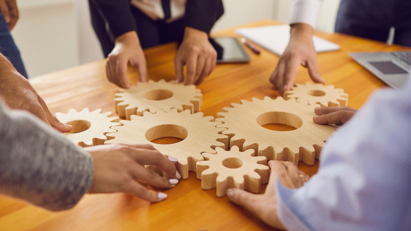 A team of people putting gears together on a table