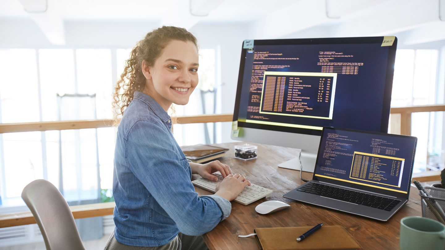 A woman sitting at a desk typing code on a computer