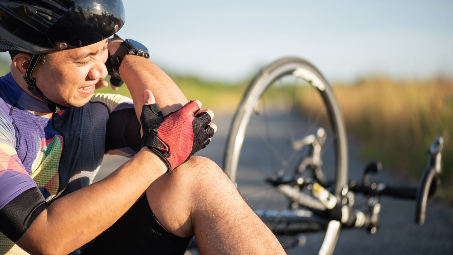 A bicyclist inspecting an injury after falling off their bike.
