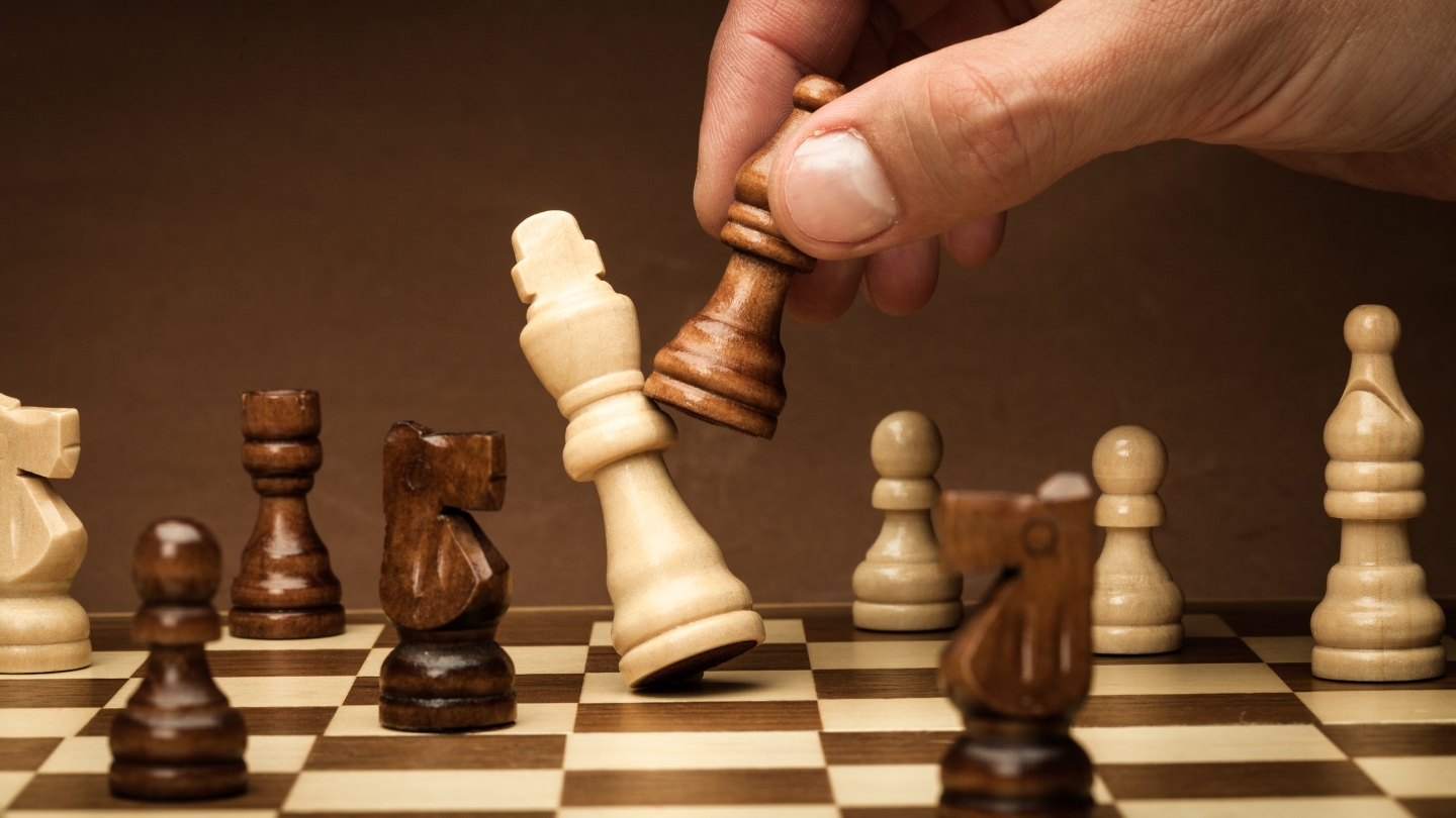 A hand moving a piece in a game of chess