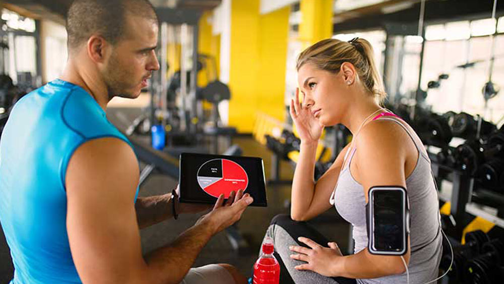 How an App Can Increase the Value of Your Current Products Gym trainer displaying app to female user