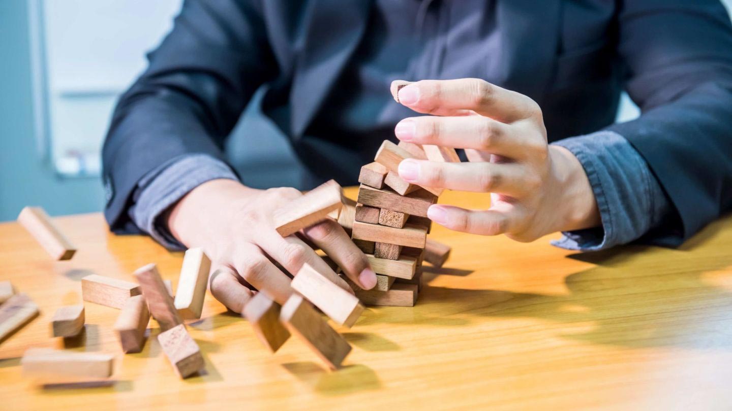 Three uncertainties that threaten every project jenga Man frustrated with Jenga pieces