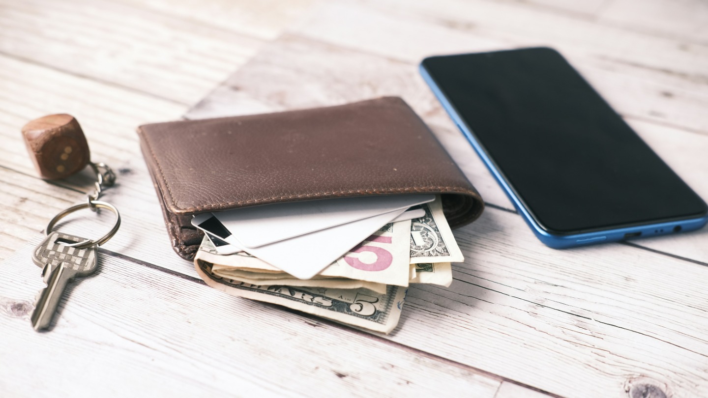 A wallet with money exposed, a smartphone and keys.